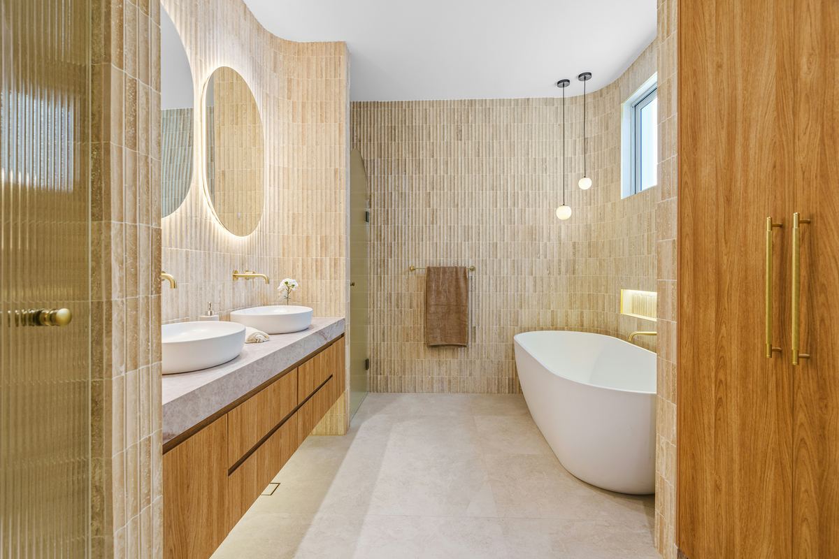 Badkamer met houten meubel, twee kommen en een vrijstaand bad